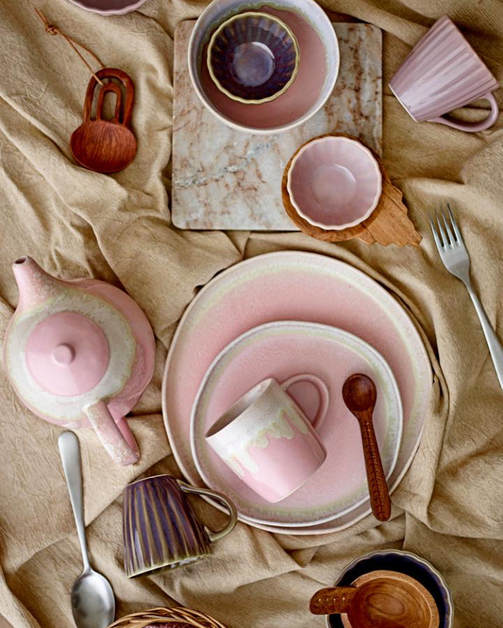 Pink ceramic tableware set on a beige fabric background