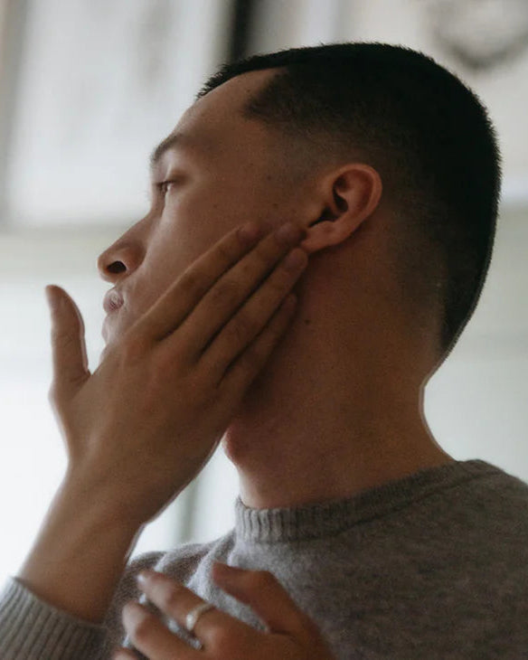 Man applying moisturizer with product details on a white background