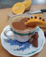 A Hot Toady made with Old tom gin in a cup with cinnamon stick, and a piece of orange with cloves 
