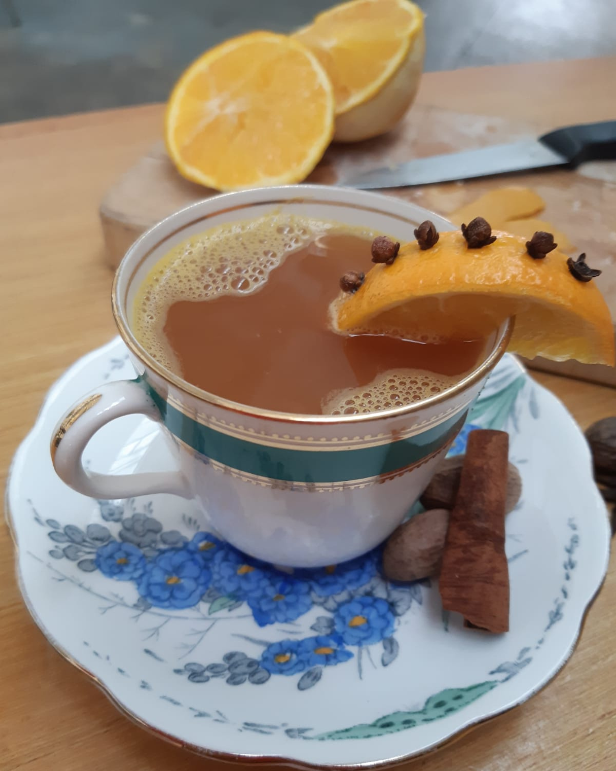 A Hot Toady made with Old tom gin in a cup with cinnamon stick, and a piece of orange with cloves 