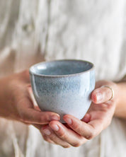 Person holding a speckled blue ceramic cup