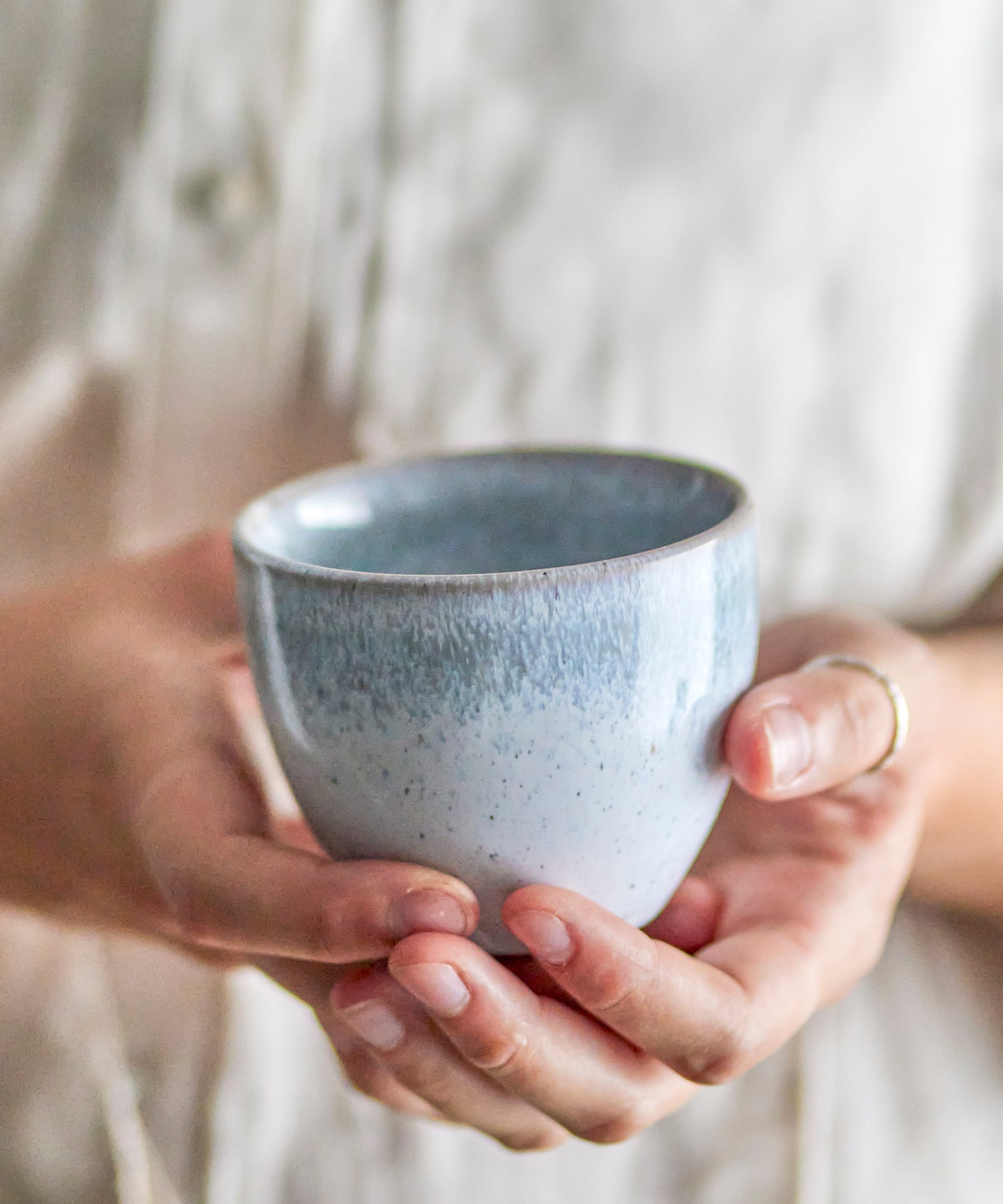 Person holding a speckled blue ceramic cup