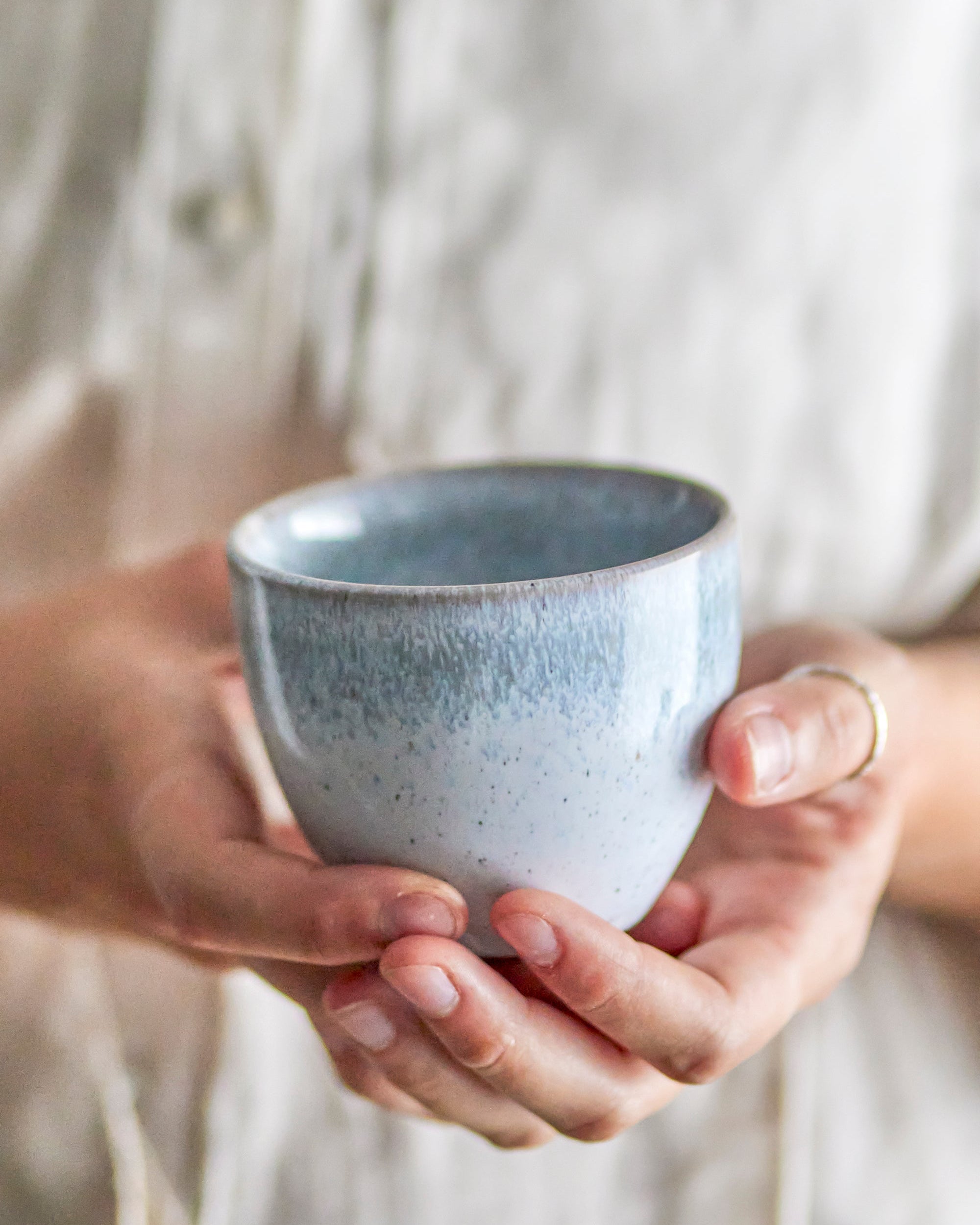 Person holding a speckled blue ceramic cup