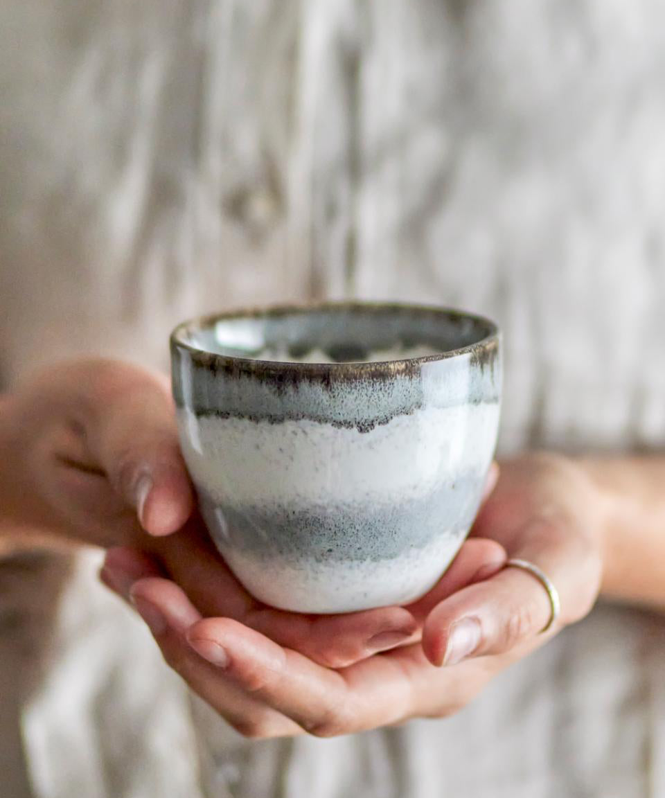 Person holding a ceramic cup with a blurred background