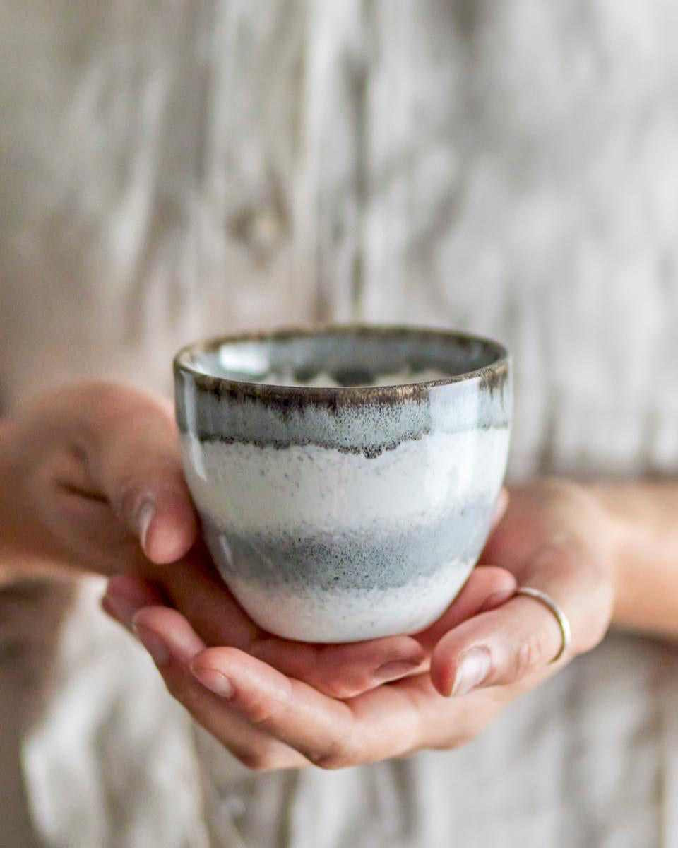 Person holding a ceramic cup with a blurred background