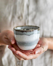 Person holding a ceramic cup with a blurred background