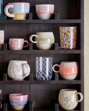 Collection of ceramic mugs on a dark wooden shelf