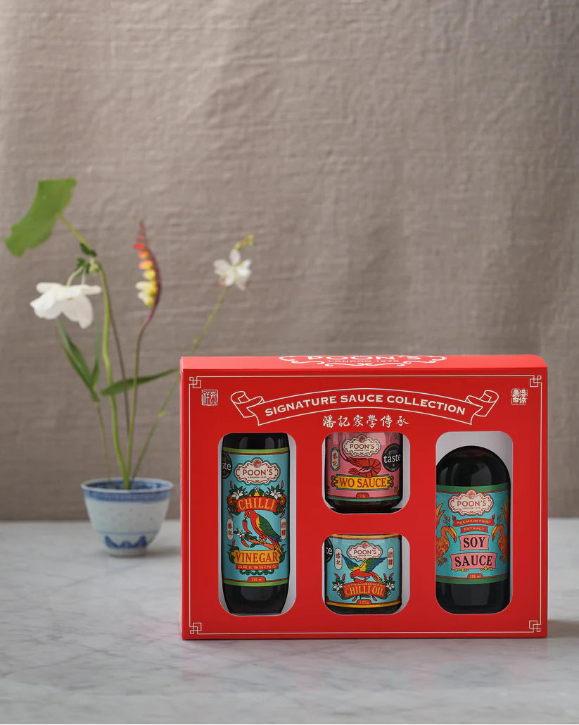 Red gift box with four sauce bottles on a neutral background