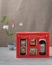 Red gift box with four sauce bottles on a neutral background