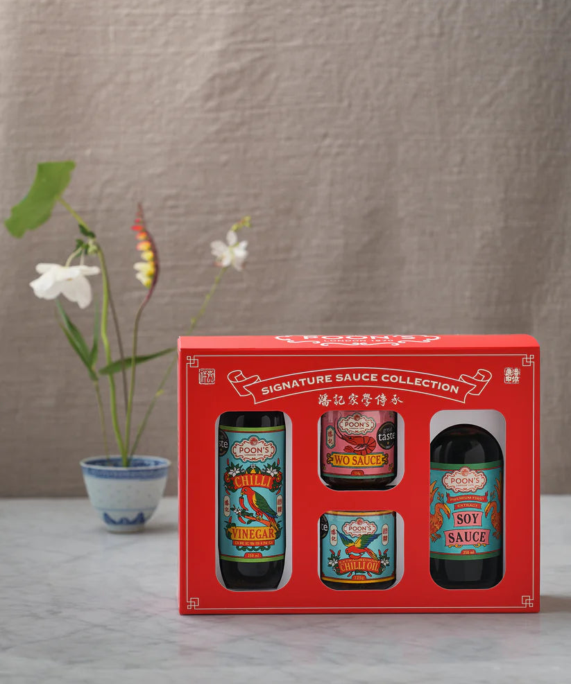 Red gift box with four sauce bottles on a neutral background