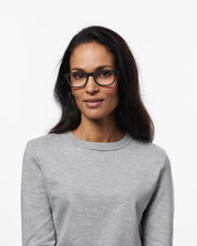 Woman wearing glasses and a gray sweater on a white background