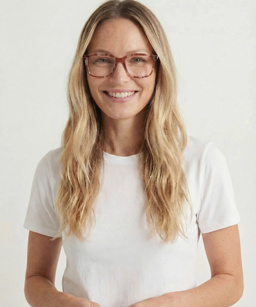 Woman wearing glasses and a white t-shirt against a plain background