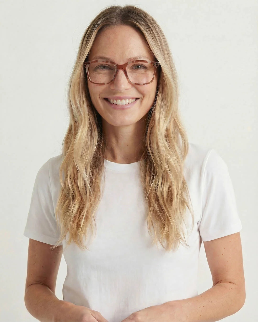 Woman wearing glasses and a white t-shirt against a plain background