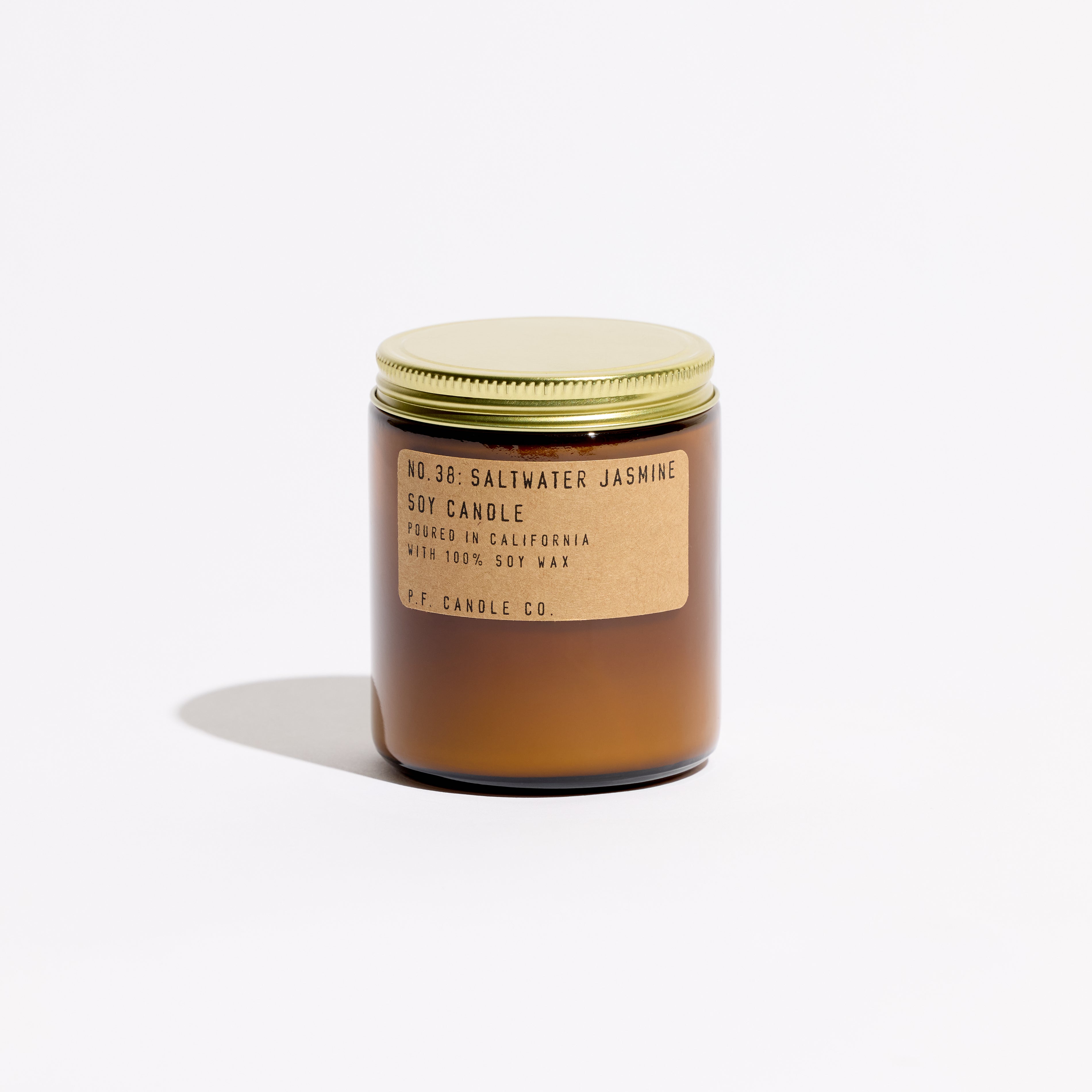 Saltwater Jasmine candle, by PF Candle Co, in an amber glass jar with a brass lid, against. a white background