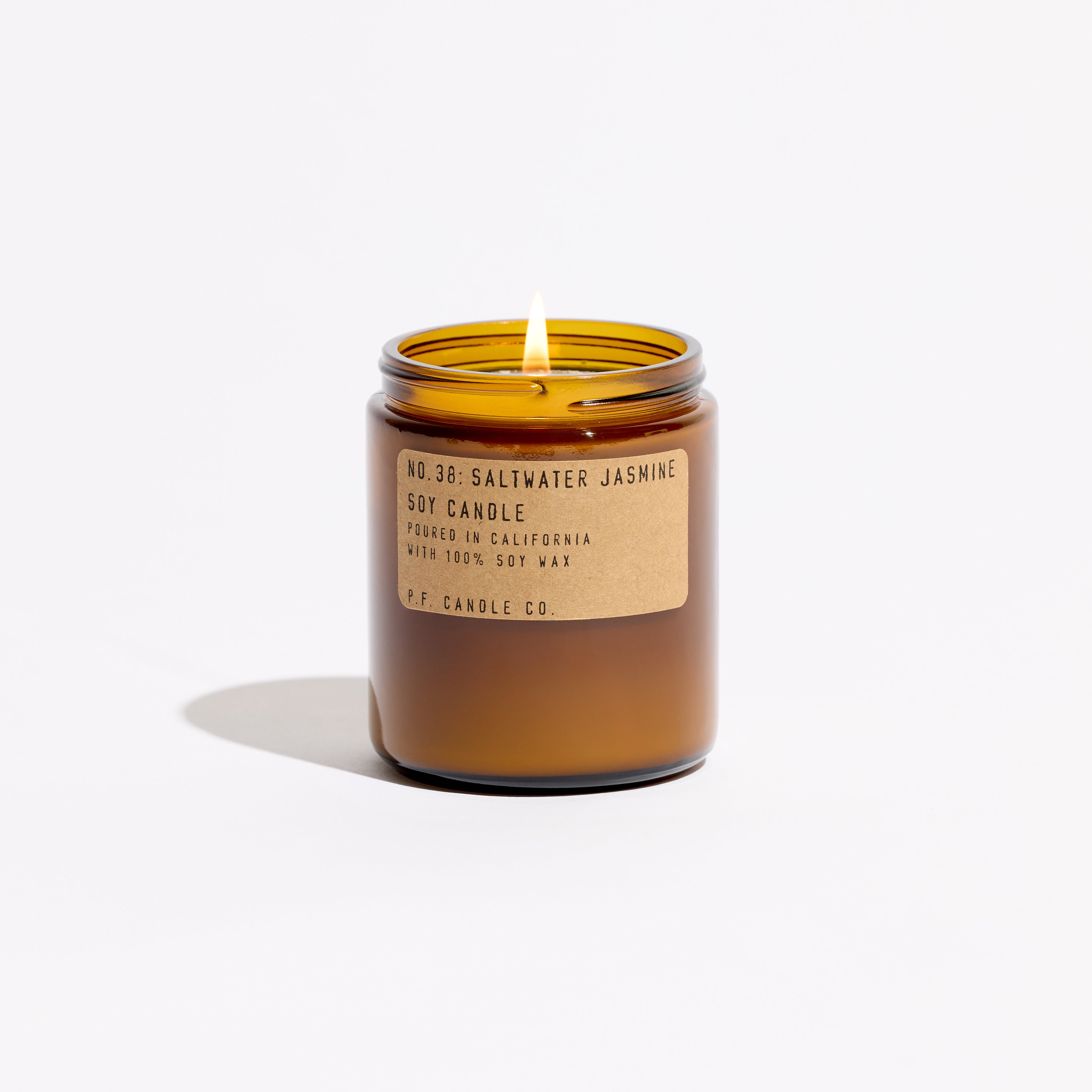 Saltwater Jasmine candle, by PF Candle Co, in an amber glass jar with a brass lid, against. a white background
