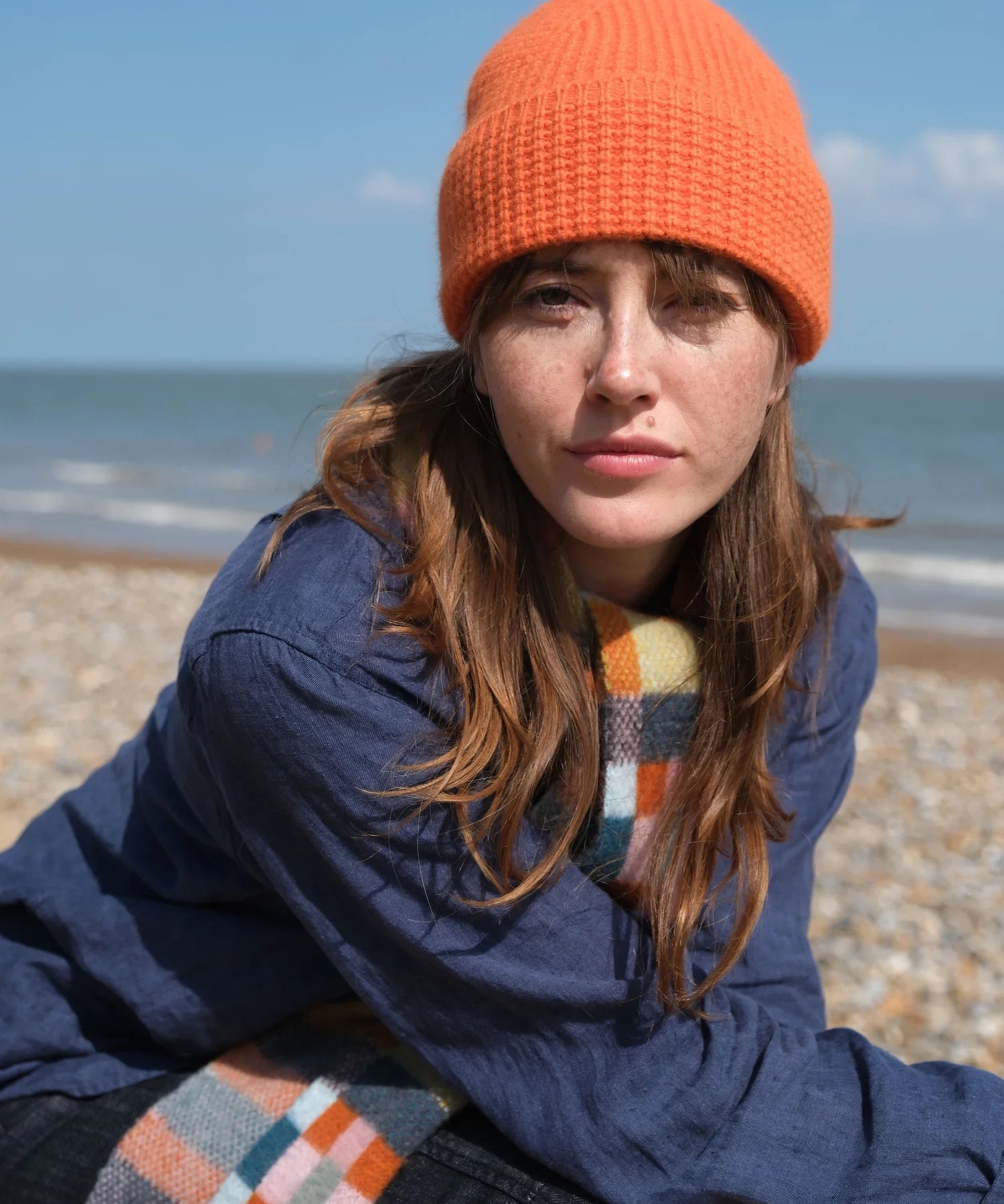 A woman on the beach wearing a tangerine beanie