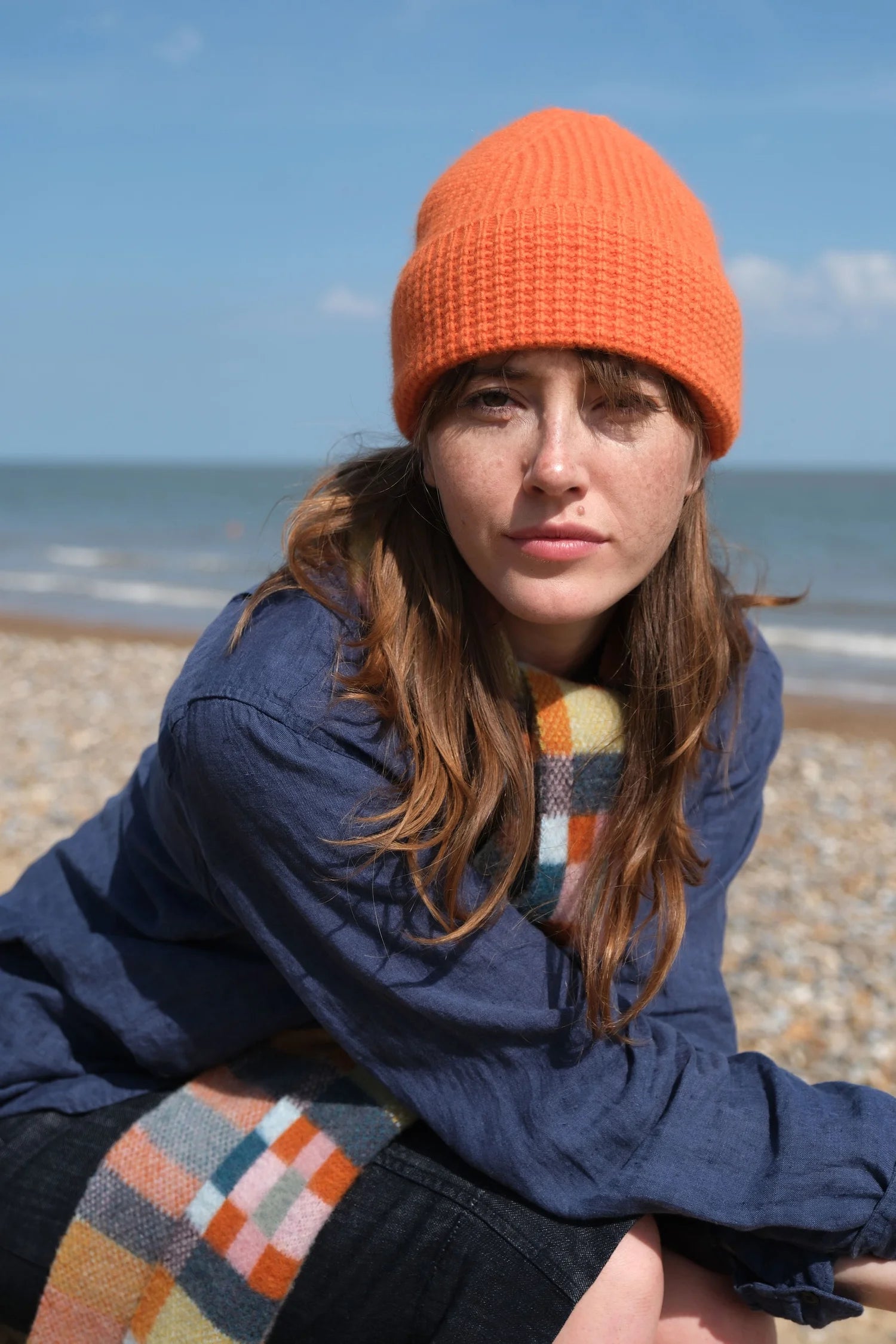 A woman on the beach wearing a tangerine beanie
