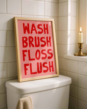 Bathroom with a framed sign on a toilet tank reading 'WASH BRUSH FLOSS FLUSH'.