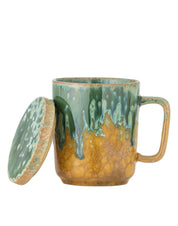 Ceramic mug with green and brown glaze on a white background