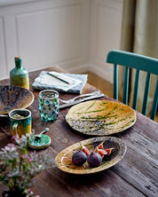Dining table with ceramic plates, glasses, and utensils on a wooden surface.
