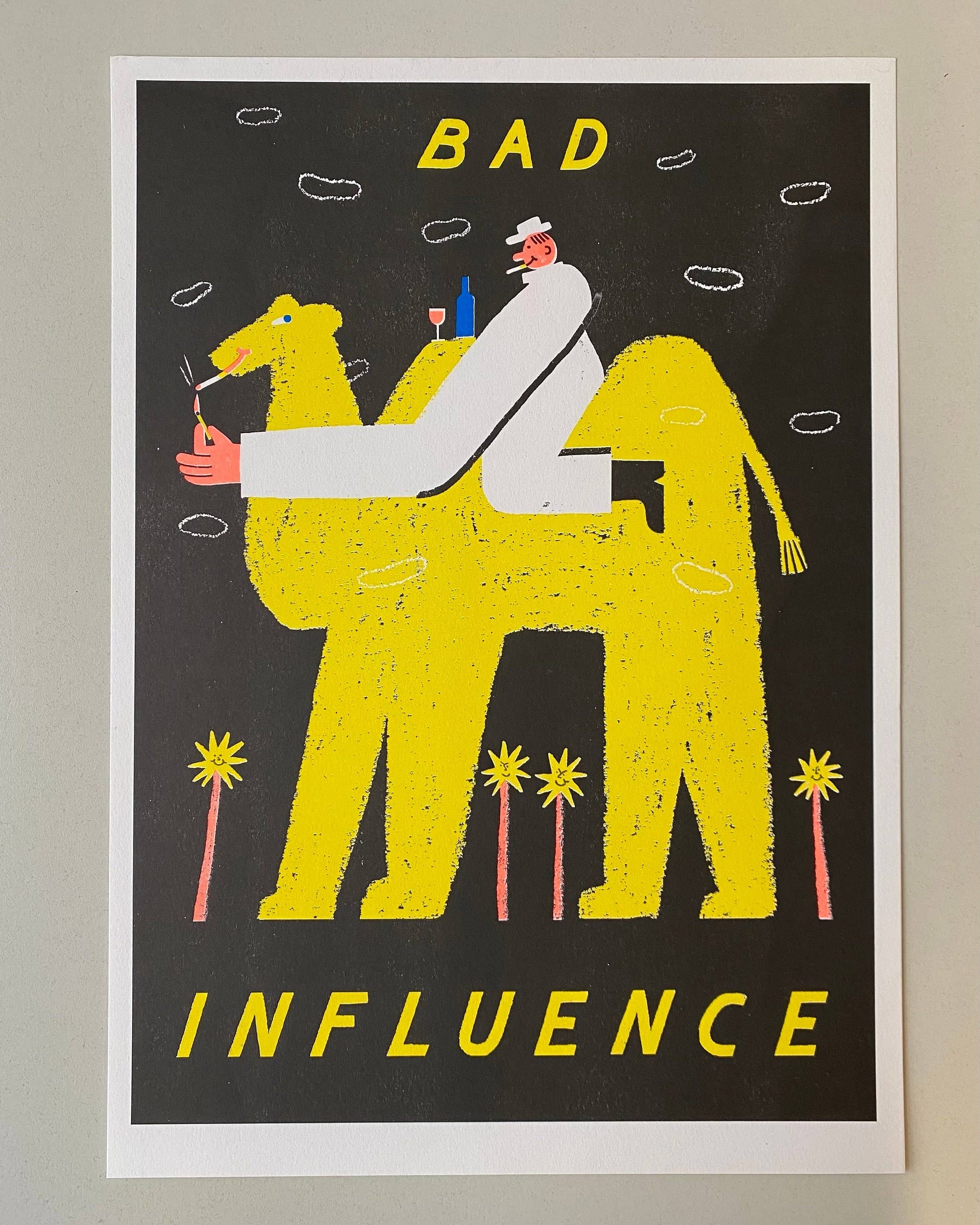 Framed artwork with a camel and person illustration and text 'Bad Influence' on a black background.