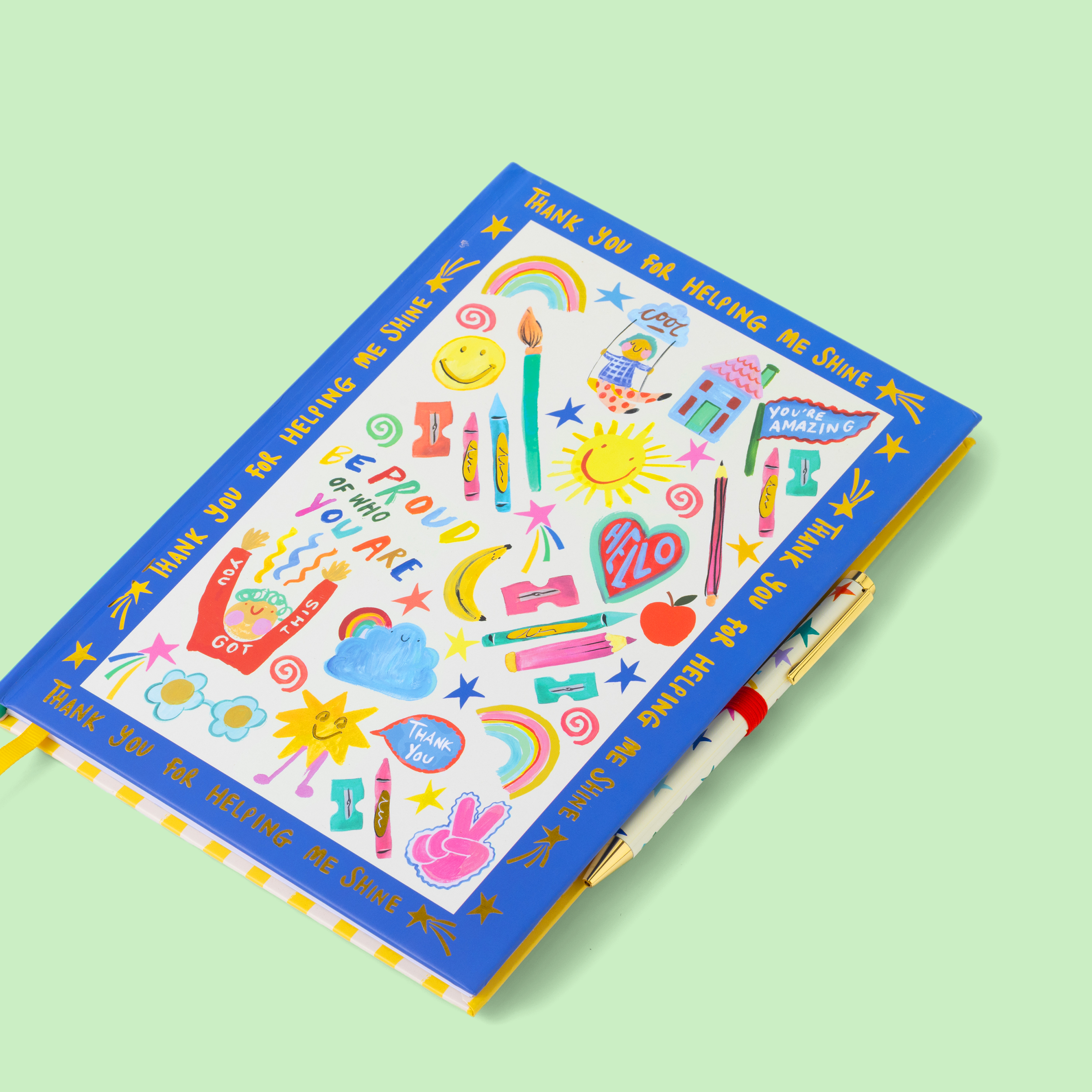 Colourful notebook with illustrations and motivational text, with matching pen, on a light green background