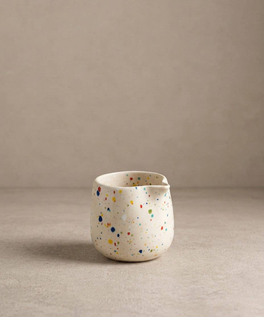 Egg Back Home white ceramic jug with multicoloured speckles on a beige background