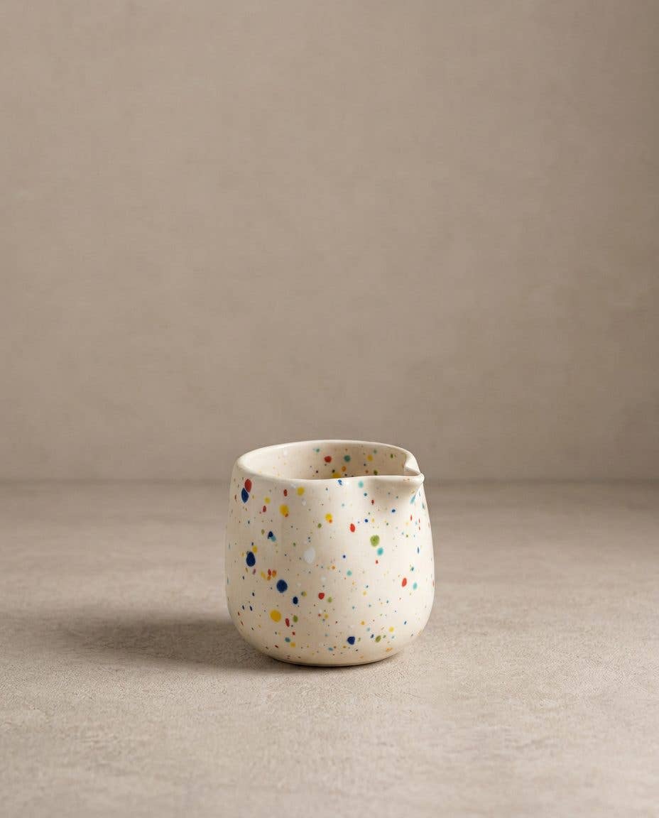 Egg Back Home white ceramic jug with multicoloured speckles on a beige background