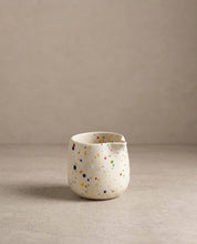 Egg Back Home white ceramic jug with multicoloured speckles on a beige background