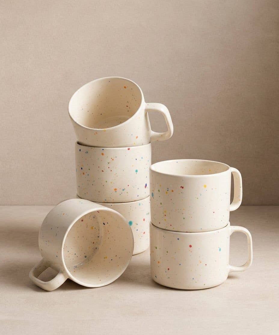 Set of Egg Back Home white ceramic mugs with colourful speckles on a neutral background