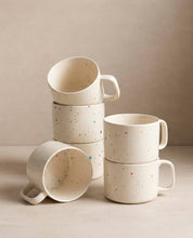 Set of Egg Back Home white ceramic mugs with colourful speckles on a neutral background