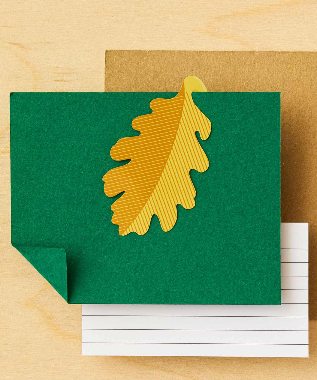 Green card with a gold leaf design on a wooden surface