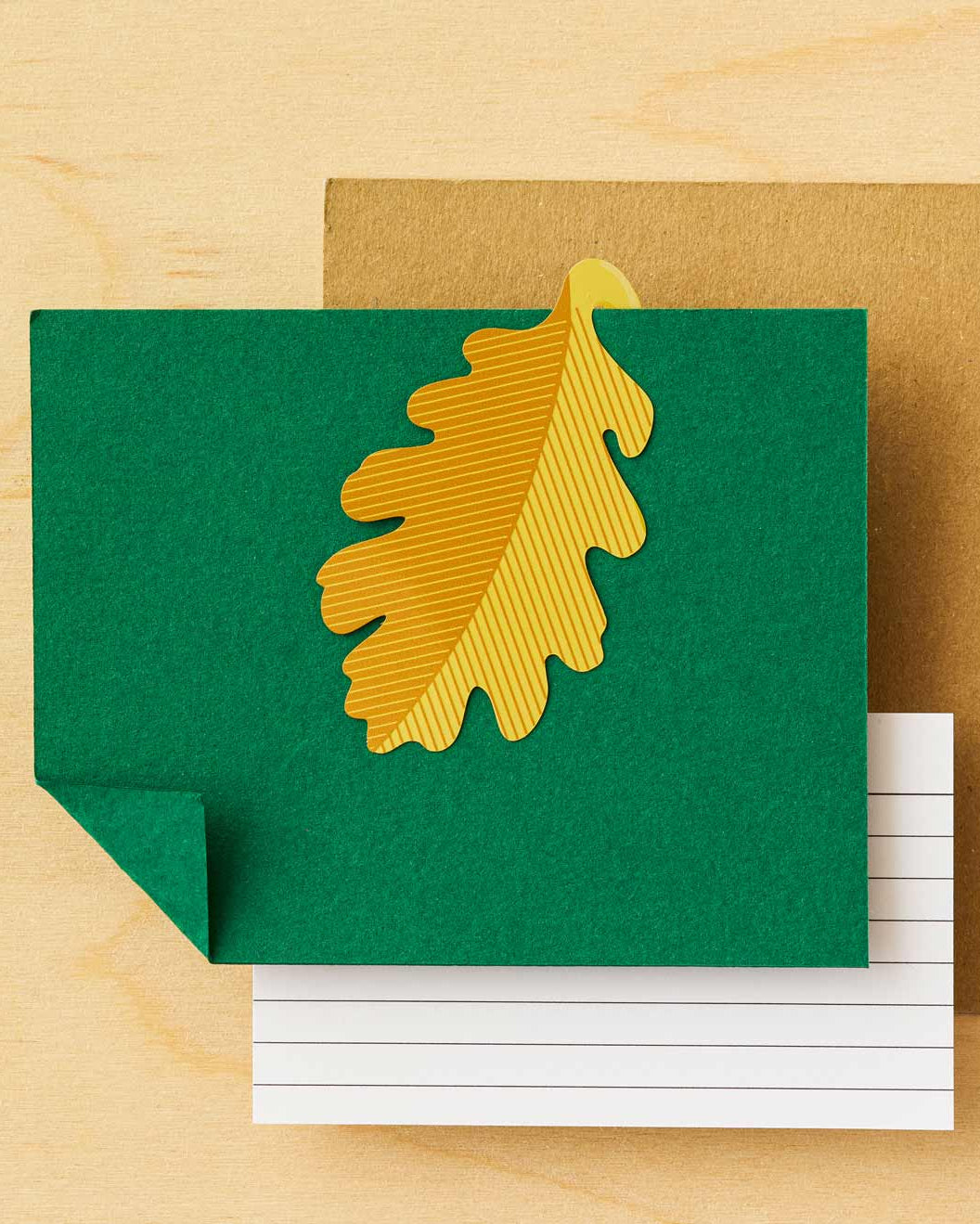 Green card with a gold leaf design on a wooden surface