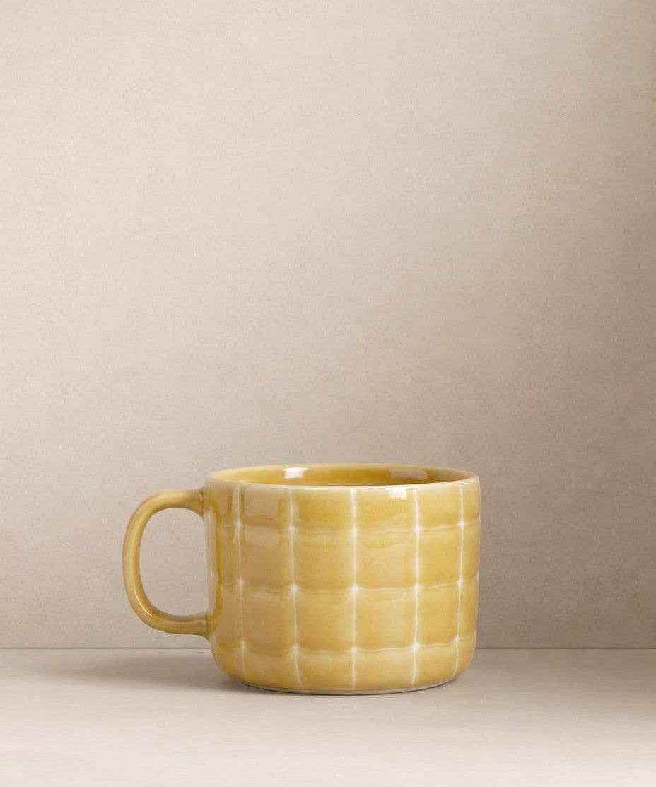 Egg Back Home yellow textured mug on a beige background
