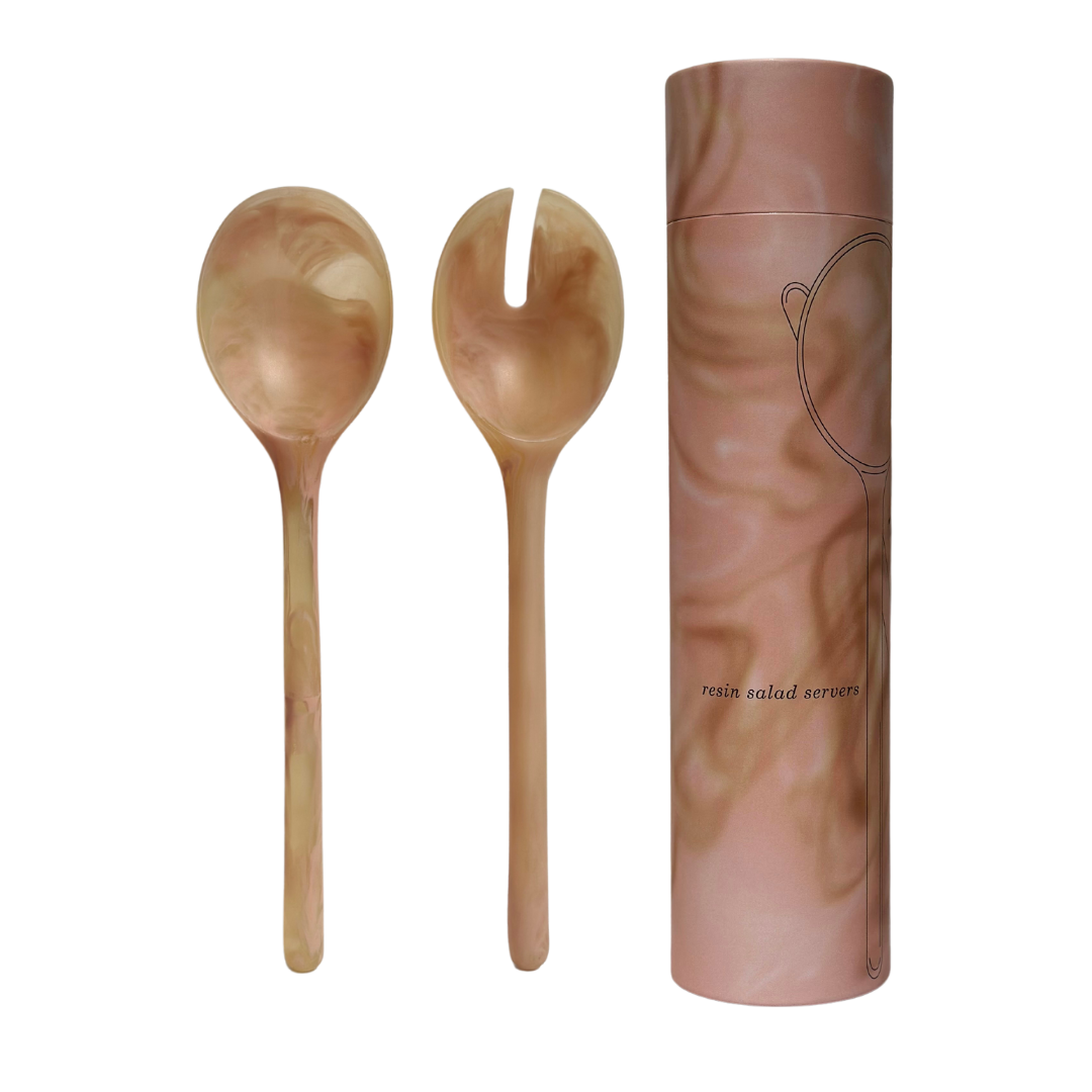 A pair of resin salad servers with a marbled coral peach pattern, including a fork and spoon, displayed alongside their cylindrical packaging.