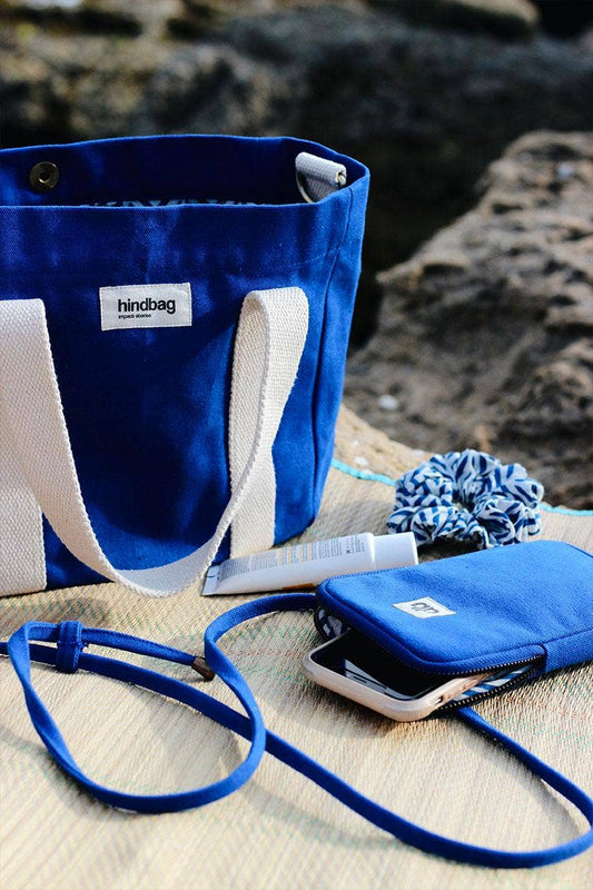 Electric blue cross body phone bag with a zipped section for phone, and a back pocket for bank cards