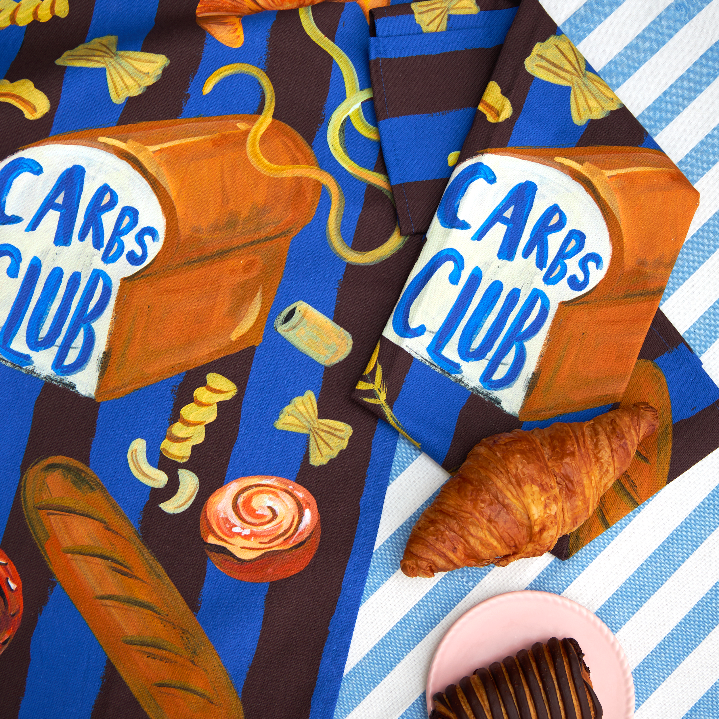 Carbs Club tea towel by Eleanor Bowmer, illustrated carbs on brown and blue stripes