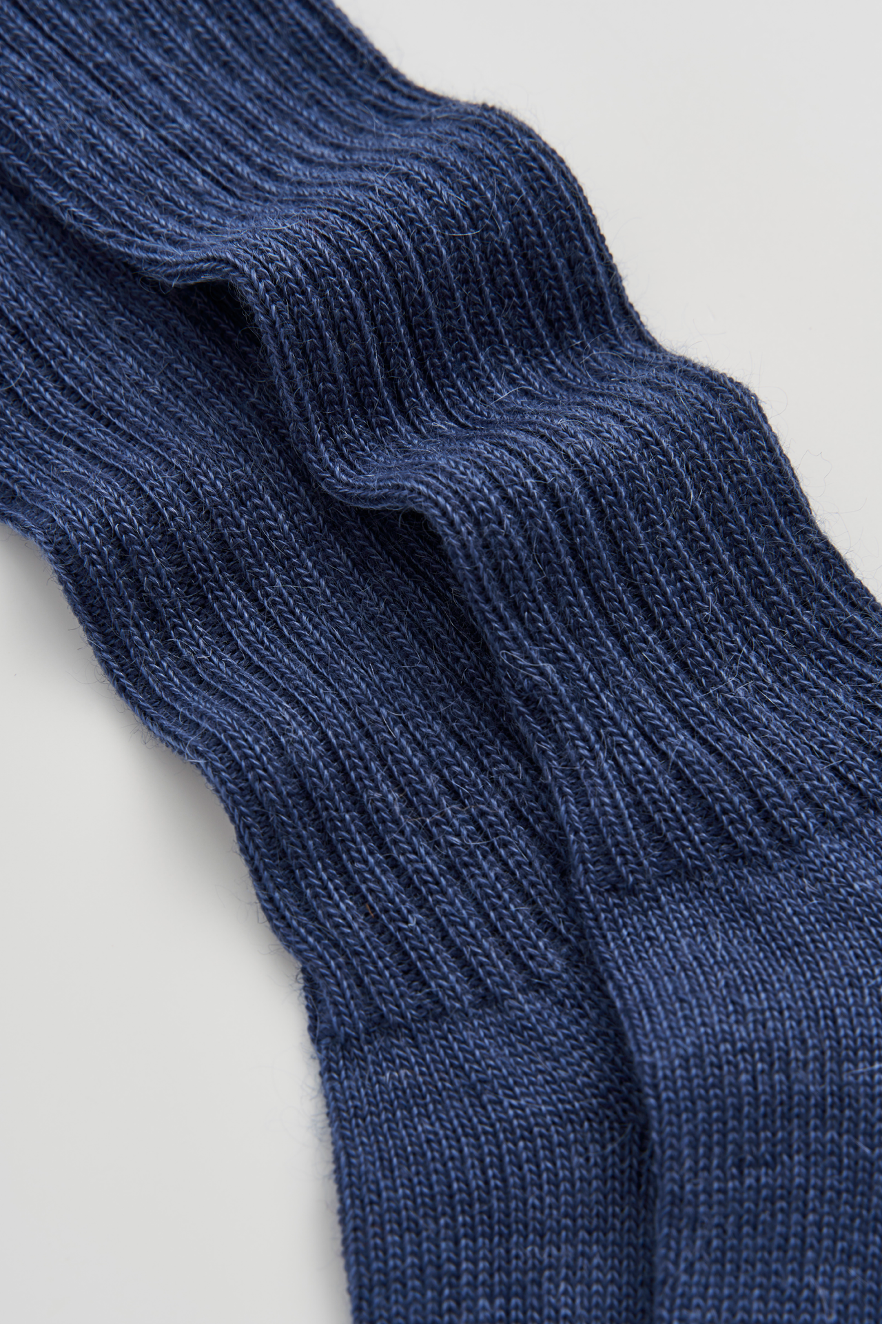 Close-up of a blue knitted sock on a light gray background