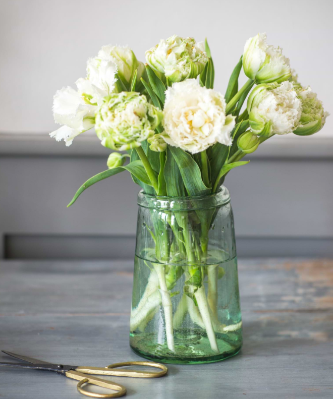 Clear vase with white flowers on a wooden surface
