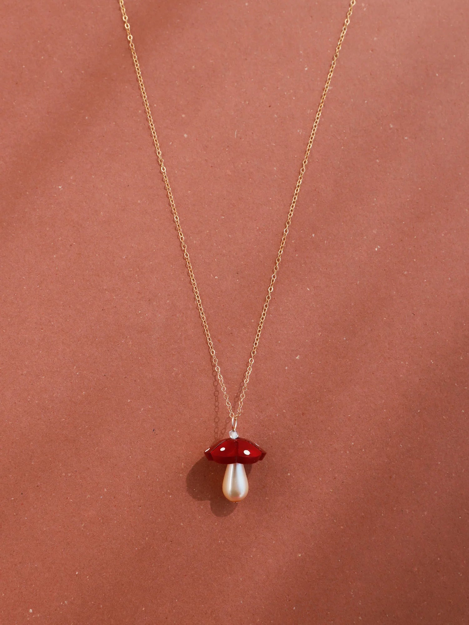 The Every Space Shroom necklace with gold filled chain and red marbled acrylic and glass pearly mushroom pendant by Wolf & Moon