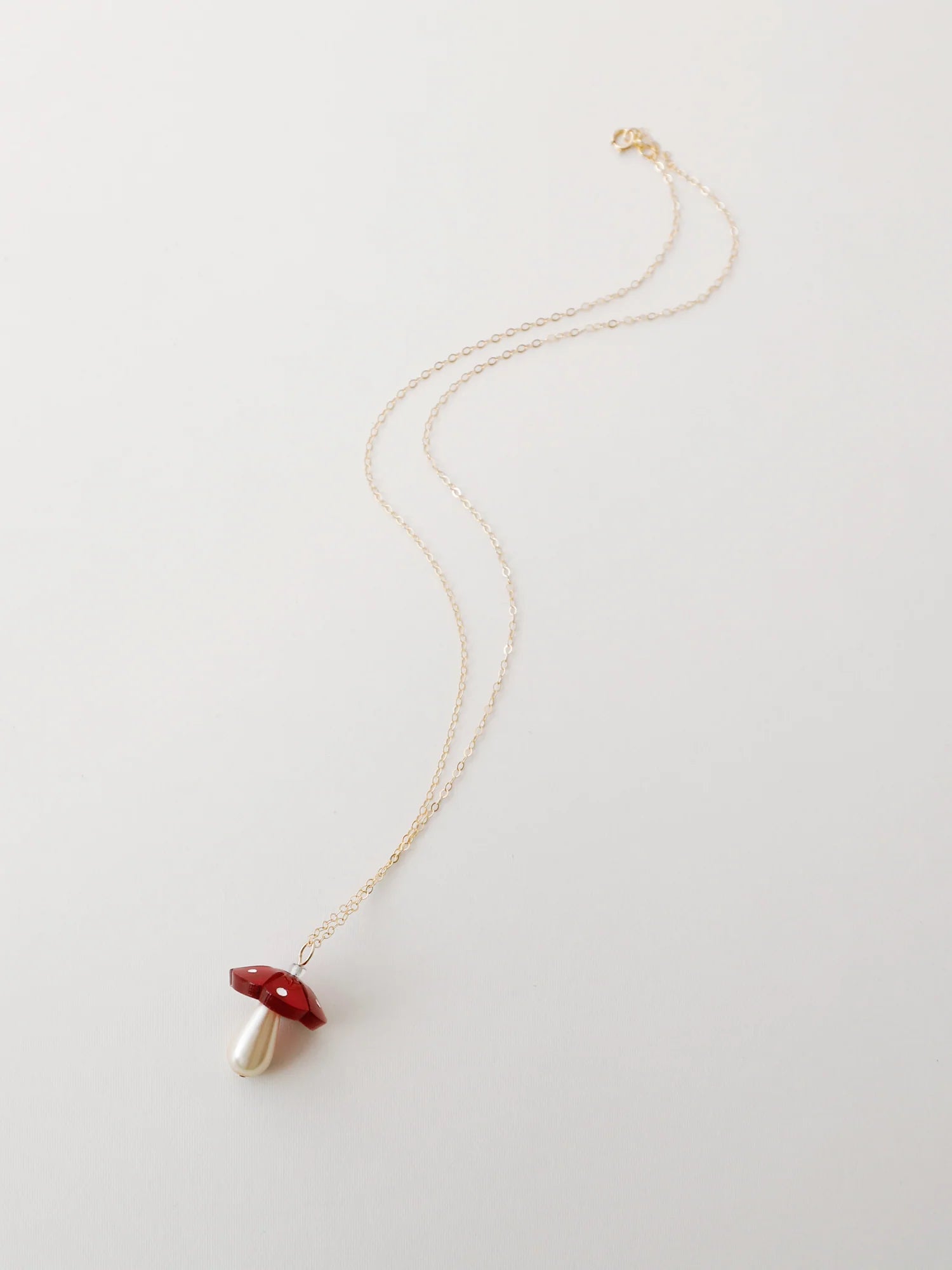 The Every Space Shroom necklace with gold filled chain and red marbled acrylic and glass pearly mushroom pendant by Wolf & Moon