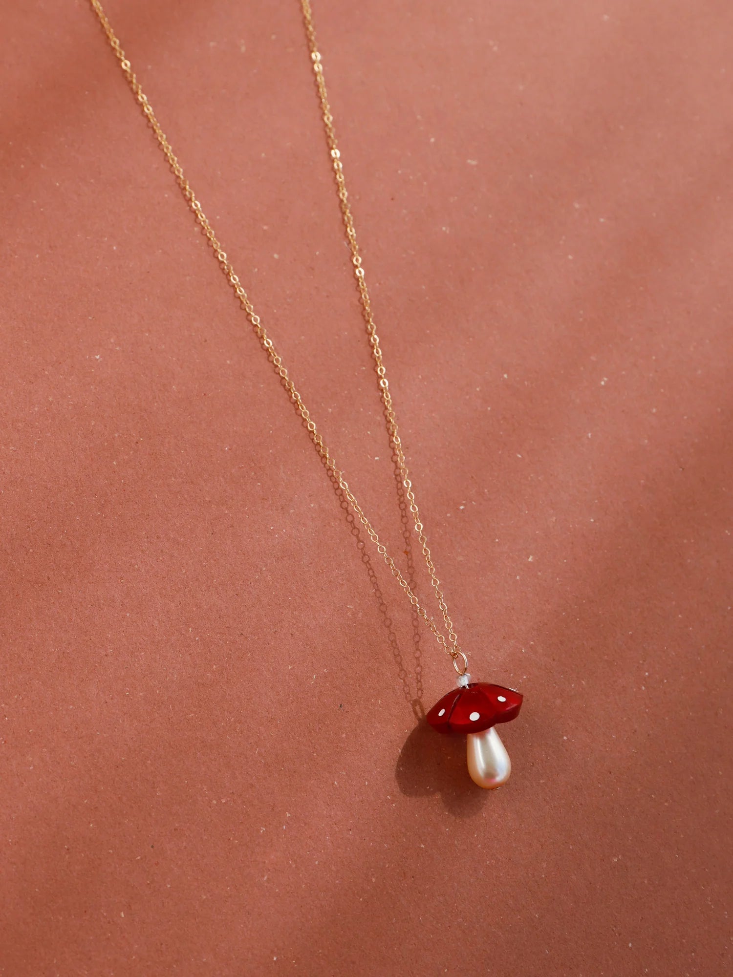 The Every Space Shroom necklace with gold filled chain and red marbled acrylic and glass pearly mushroom pendant by Wolf & Moon